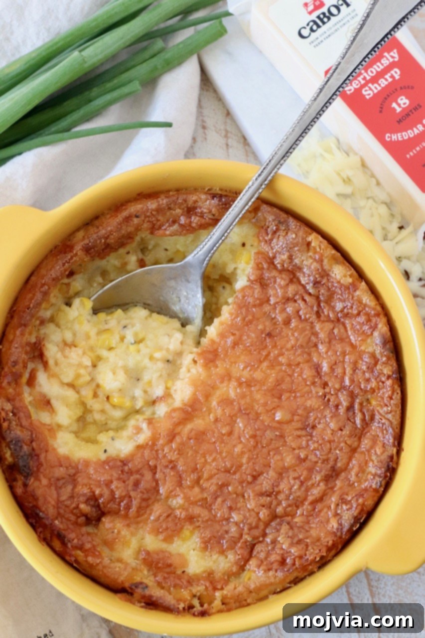 Golden Corn & Cheddar Delight 2 golden corn casserole in a yellow baking dish with a serving spoon, ready to be enjoyed