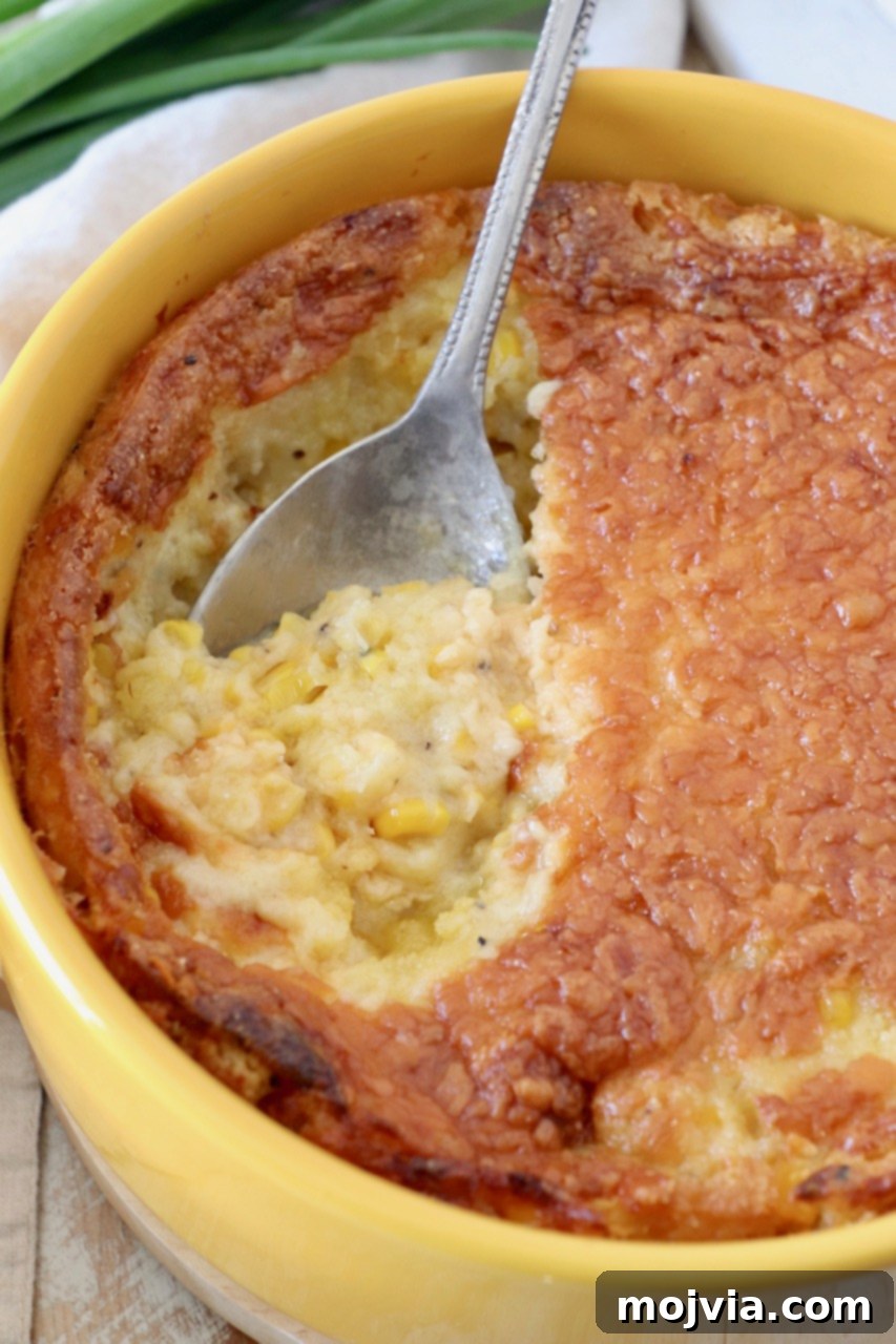 Golden Corn & Cheddar Delight 6 a round yellow baking dish filled with cheesy corn casserole, with a serving spoon resting inside
