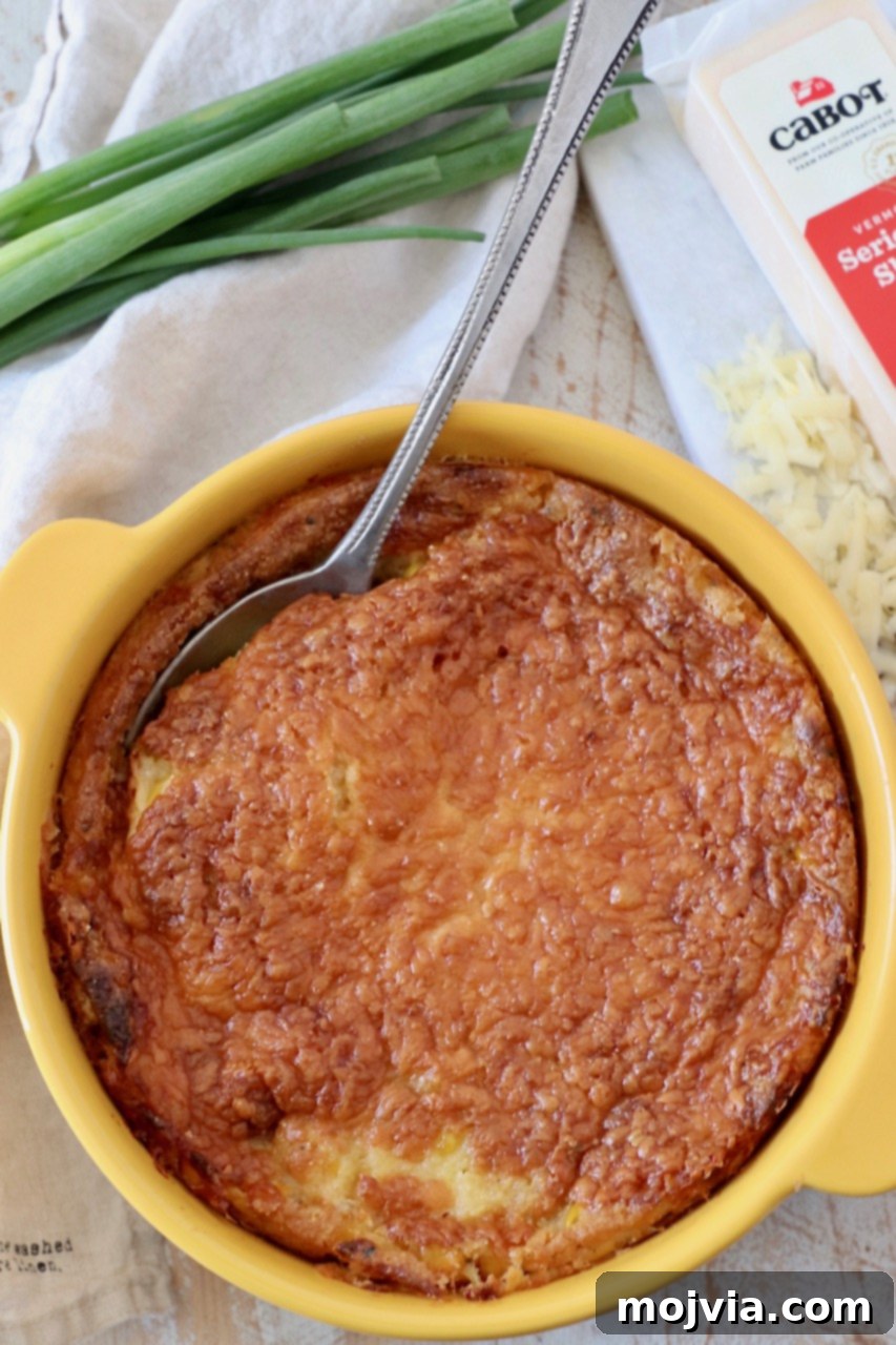 Golden Corn & Cheddar Delight 7 baked corn casserole in a yellow baking dish with a serving spoon, ready for a meal