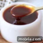 Stir fry sauce in a small white bowl with a gold spoon dipped into the sauce, representing the final delicious product.
