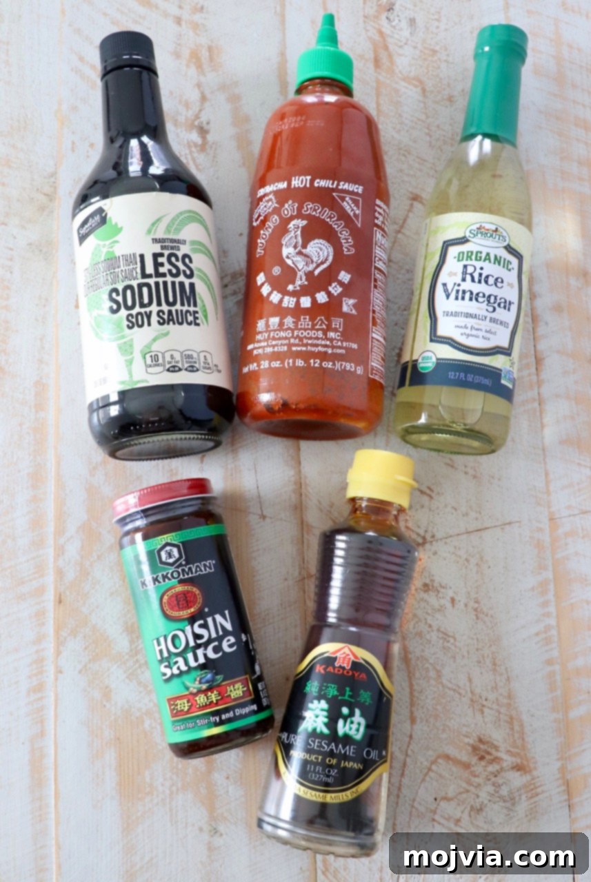 Perfect Stir-Fry Sauce 3 A collection of the five essential ingredients for making the best homemade stir fry sauce: hoisin sauce, soy sauce, rice vinegar, sesame oil, and sriracha, neatly arranged in small white bowls, ready for mixing.