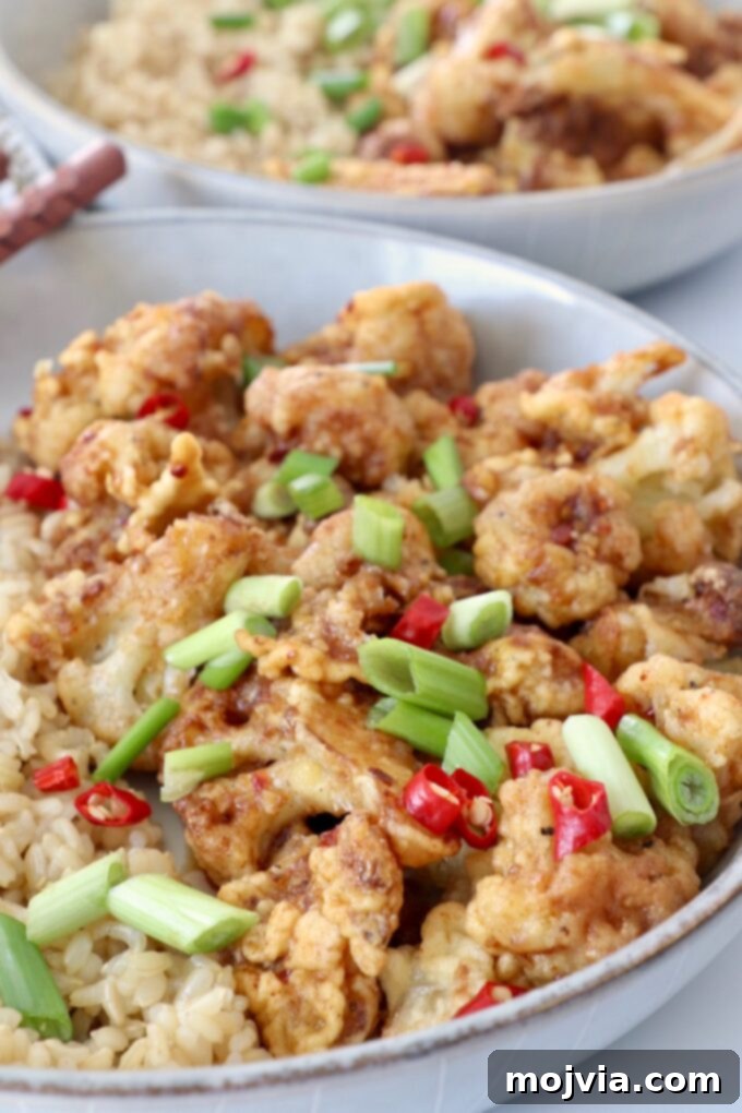 Spicy Tso Style Cauliflower Bites 5 fried cauliflower tossed with general tso's sauce in bowl with brown rice