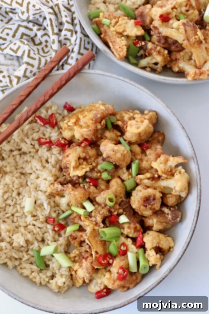 Spicy Tso Style Cauliflower Bites 6 fried cauliflower in bowl with brown rice and chopsticks