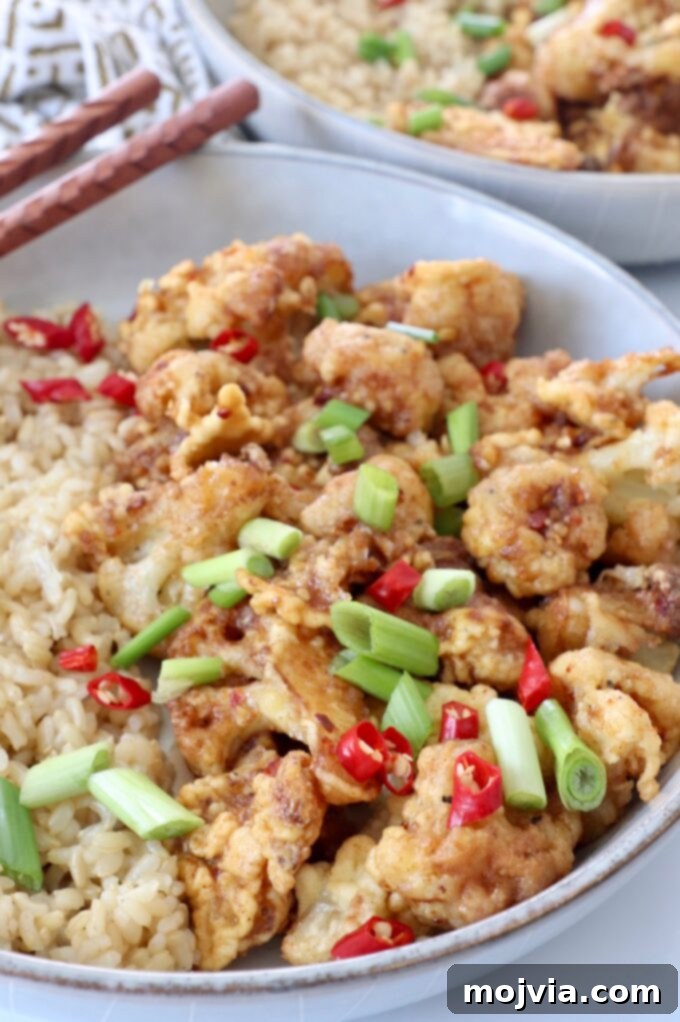 Spicy Tso Style Cauliflower Bites 7 fried general tso cauliflower in bowl with diced red chilies and green onions