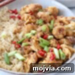 Spicy Tso Style Cauliflower Bites 8 general tso's cauliflower in bowl with diced green onions, red peppers and brown rice