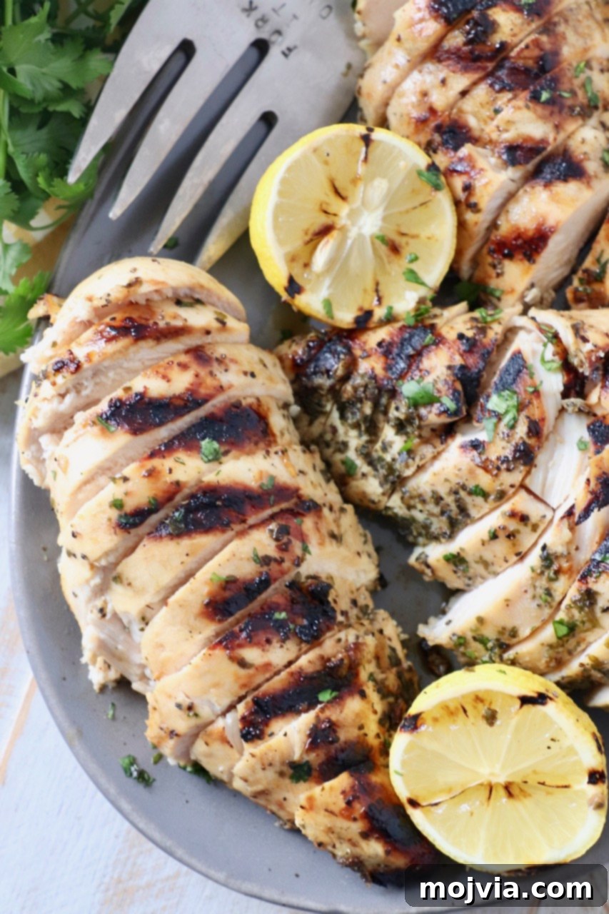Greek Lemon Herb Chicken Marinade 2 sliced grilled chicken on plater with fork and lemon slices