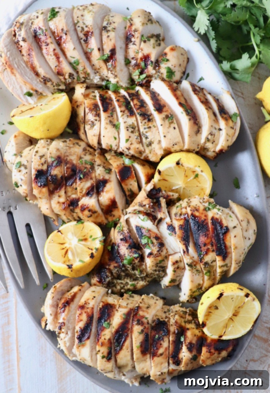Greek Lemon Herb Chicken Marinade 5 sliced grilled chicken breasts on plate with lemons
