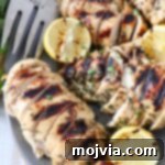 Greek Lemon Herb Chicken Marinade 8 sliced grilled chicken on plate with lemons