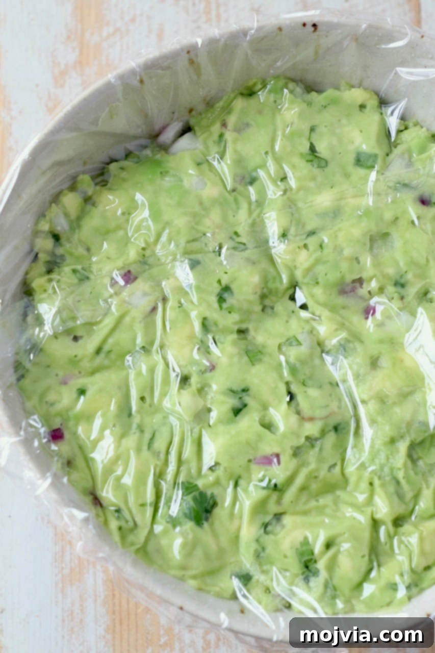 guacamole in bowl with plastic wrapped pressed on top