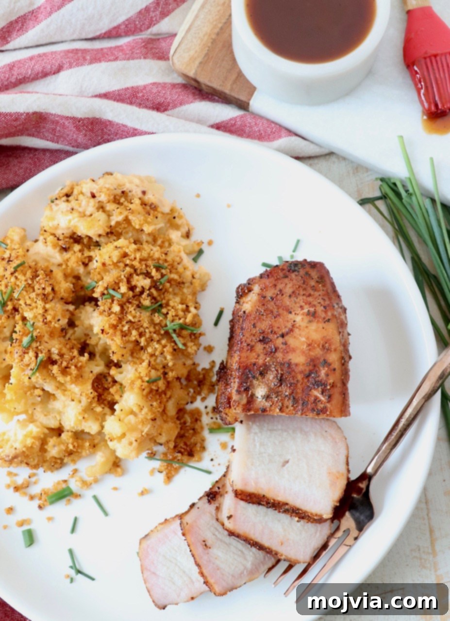 Artisan Smoked Pork Chops 12 A serving of sliced smoked pork chop alongside mac and cheese on a plate, highlighting the delicious texture.