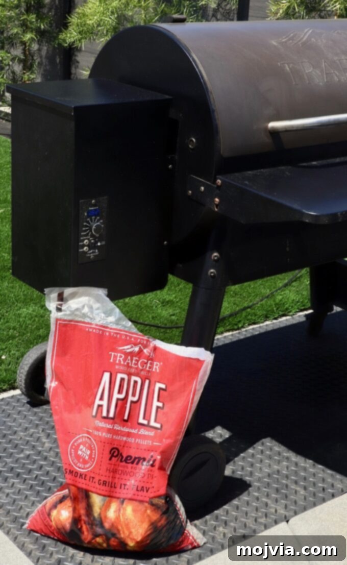 Artisan Smoked Pork Chops 5 A bag of applewood pellets placed next to a smoker outdoors, indicating the choice of wood for smoking.