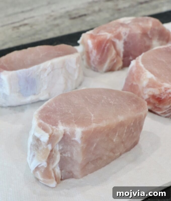 Artisan Smoked Pork Chops 6 Thick pork chops laid out on paper towels on a cutting board, being patted dry after brining.