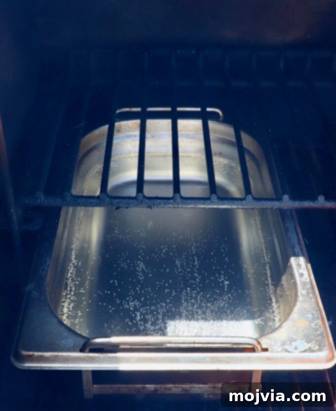 Artisan Smoked Pork Chops 8 A pan filled with water placed inside a smoker, essential for maintaining moisture during the smoking process.