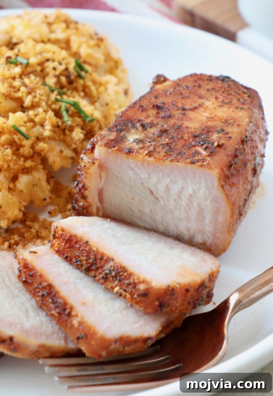 Artisan Smoked Pork Chops 10 A perfectly cooked, sliced smoked pork chop served on a plate with a side of creamy mac and cheese.