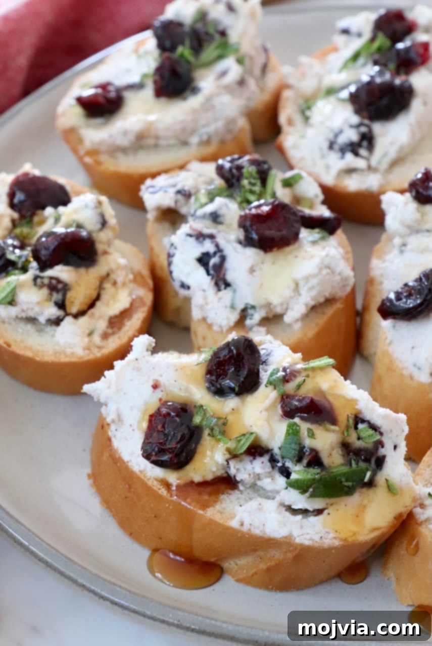 Creamy Goat Cheese and Tart Cranberry Crostini 5 cranberry goat cheese crostini drizzled with honey on a plate