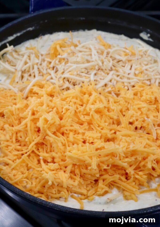 Velvet Smoke Mac 9 shredded cheese in skillet of creamy sauce