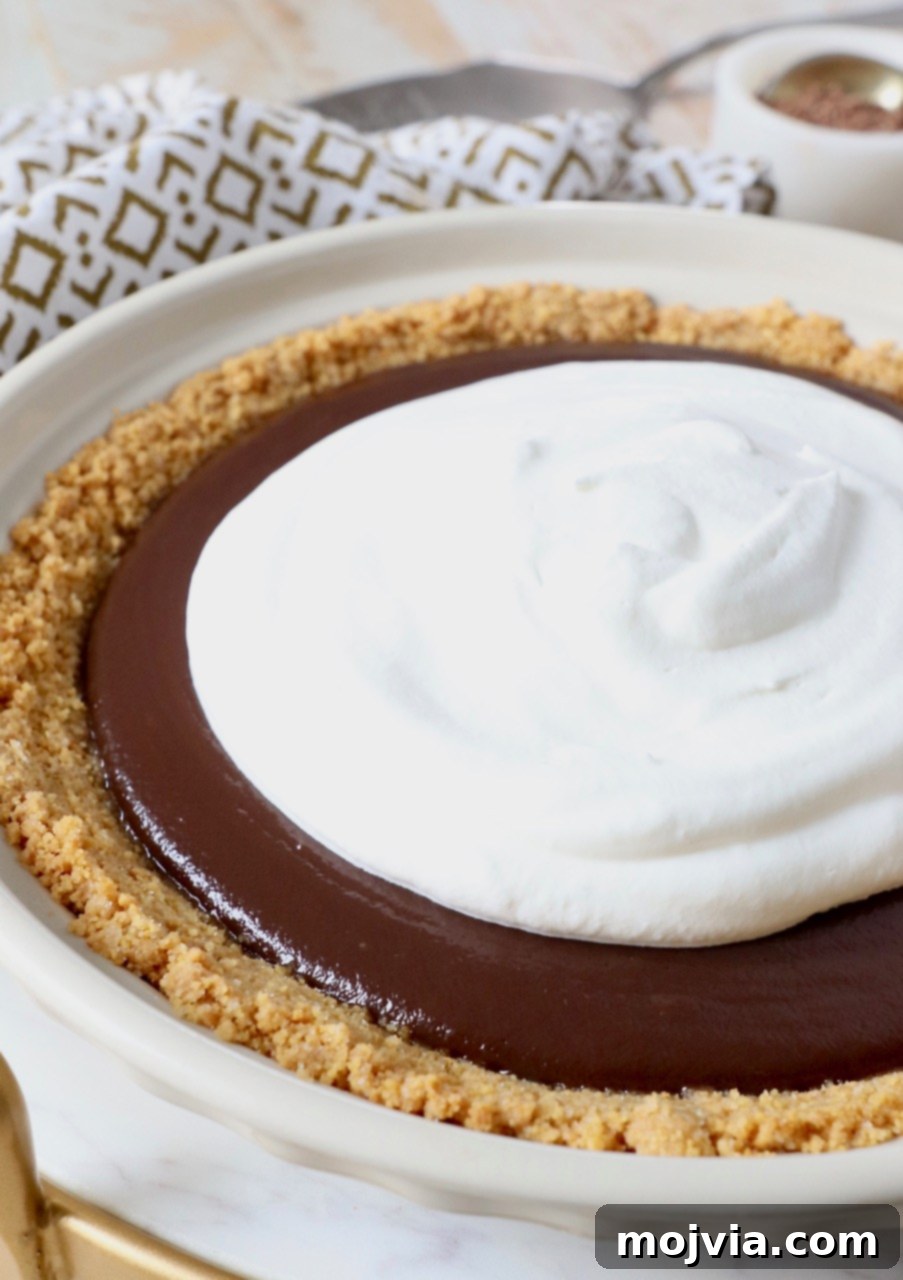 A beautifully chilled homemade chocolate pie generously topped with freshly whipped cream in a classic pie plate, ready to be served.