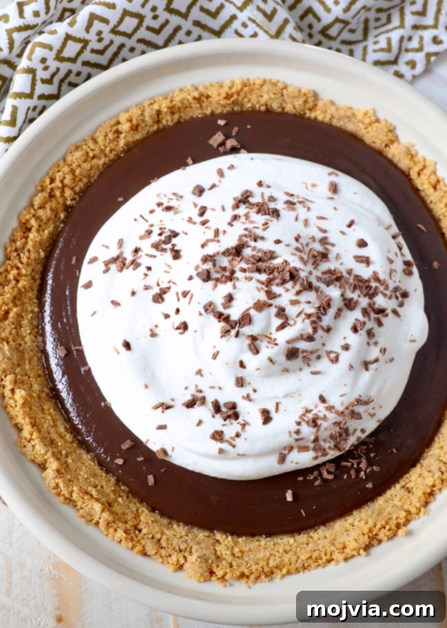 A magnificent slice of Meme's Famous Chocolate Pie, adorned with fluffy whipped cream and delicate chocolate shavings, showcasing its irresistible appeal.