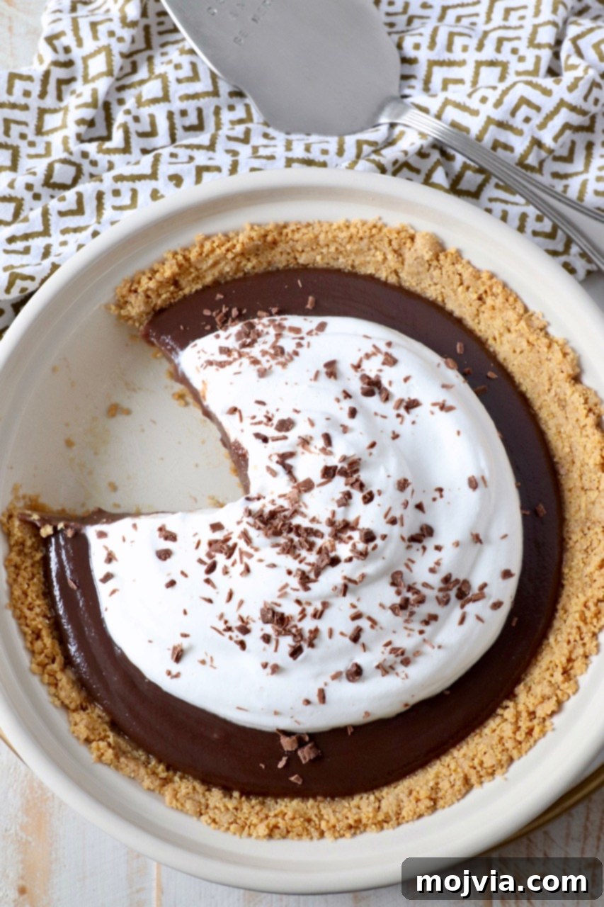 A perfectly set slice of Meme's homemade chocolate pie removed from the dish, highlighting the contrast between the rich filling and the crisp graham cracker crust.