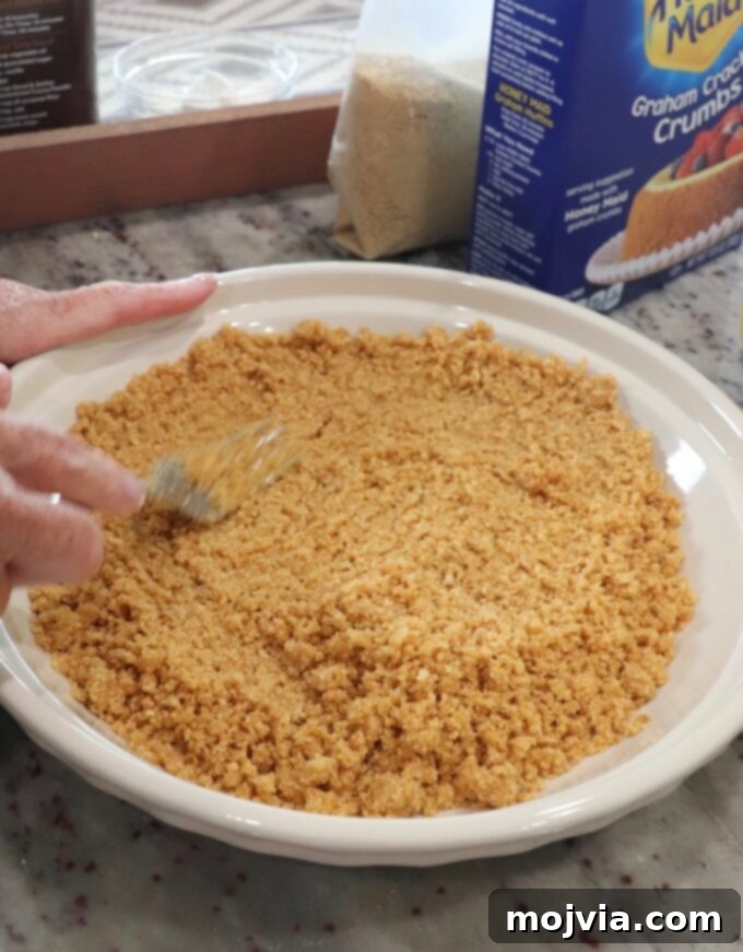 Combining graham cracker crumbs, sugar, and melted butter in a bowl to prepare the crust for Meme's chocolate pie.