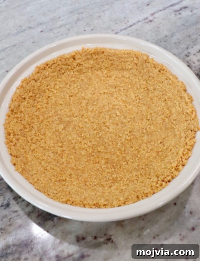 The prepared graham cracker crust, golden brown and perfectly baked, resting in a pie plate.