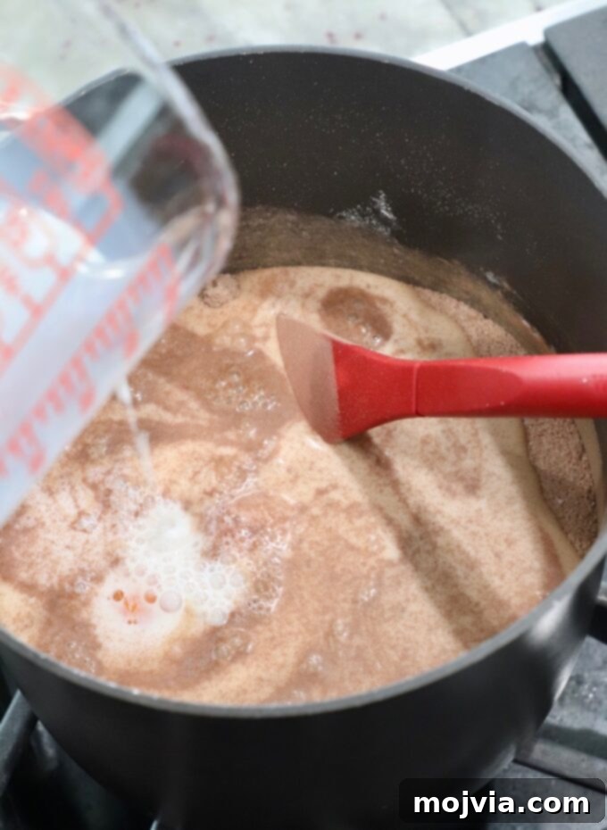 Milk being poured into a saucepan containing the mixed dry ingredients and egg yolks for the chocolate pie filling.