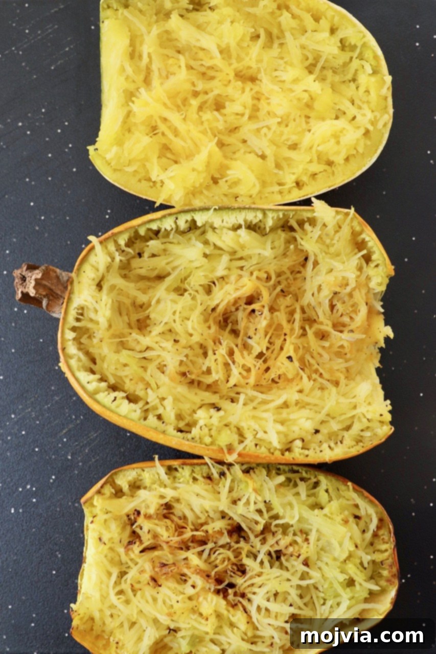 three halves of cooked spaghetti squash on cutting board