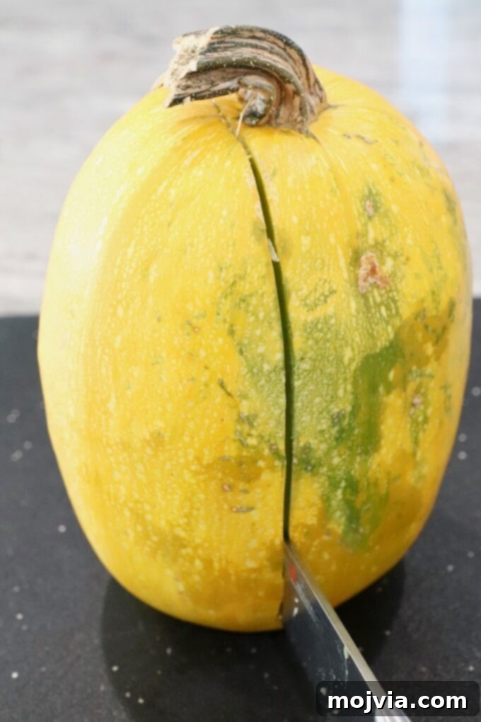 spaghetti squash on cutting board with knife slicing through the middle