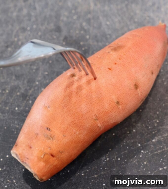 Sweet Potato Perfection Every Time 4 fork piercing a sweet potato on a cutting board, preparing it for baking