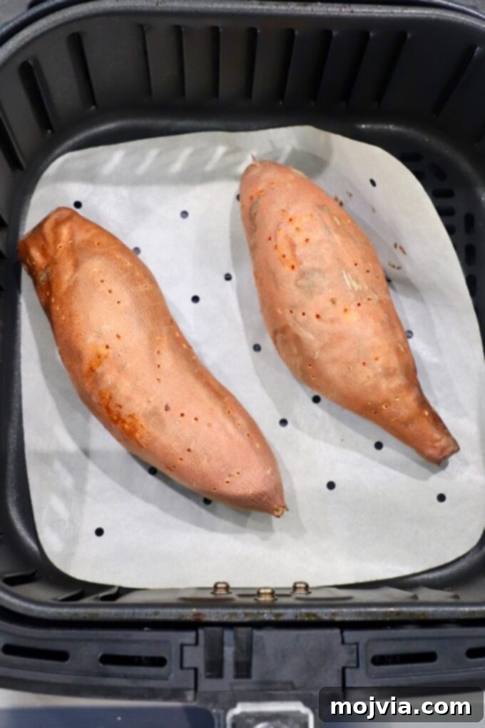 Sweet Potato Perfection Every Time 7 perfectly cooked sweet potatoes nestled in an air fryer basket, showing crispy skins