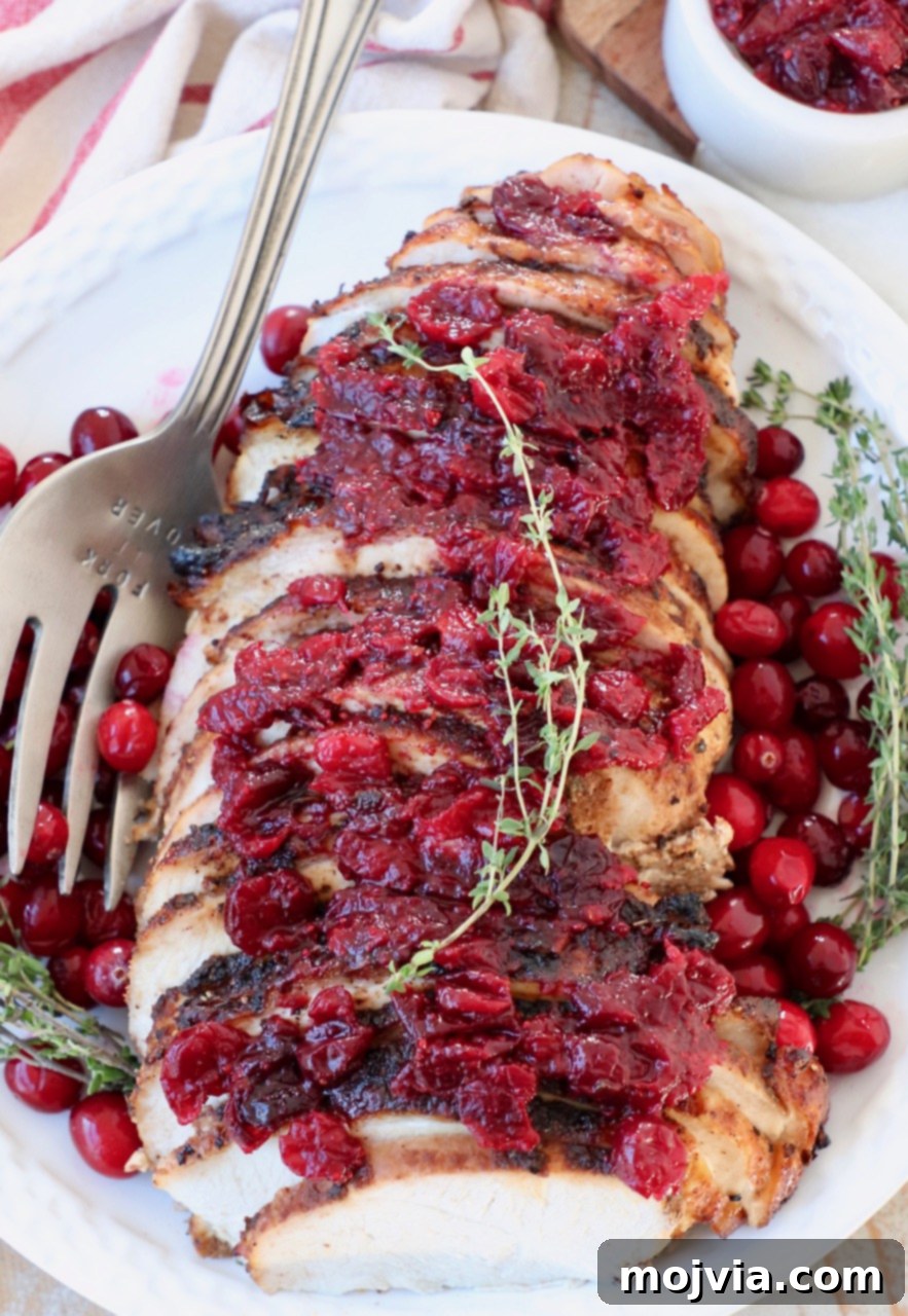 Sliced cranberry glazed turkey breast on a plate with a carving fork.