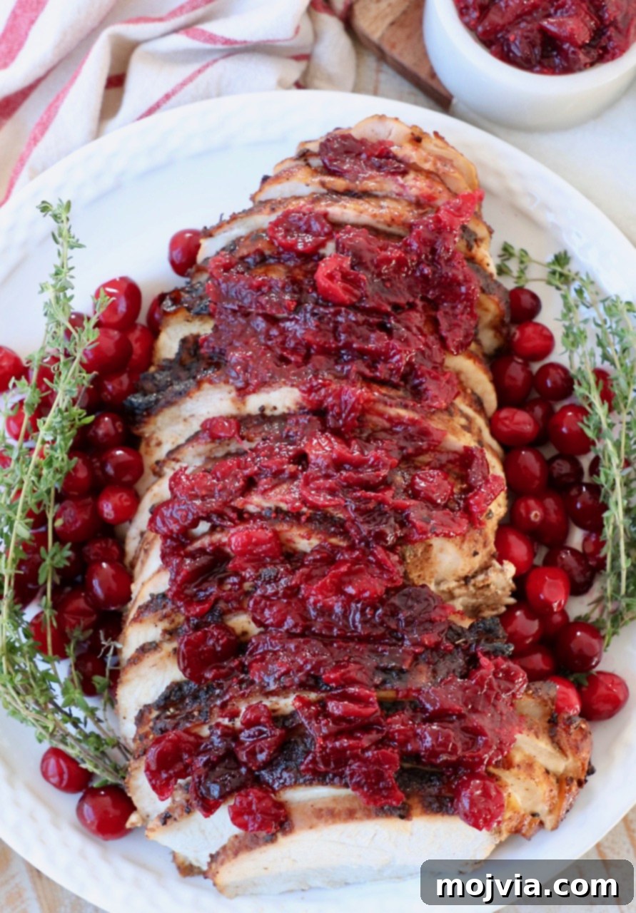 Platter with sliced turkey breast, fresh cranberries, and thyme.