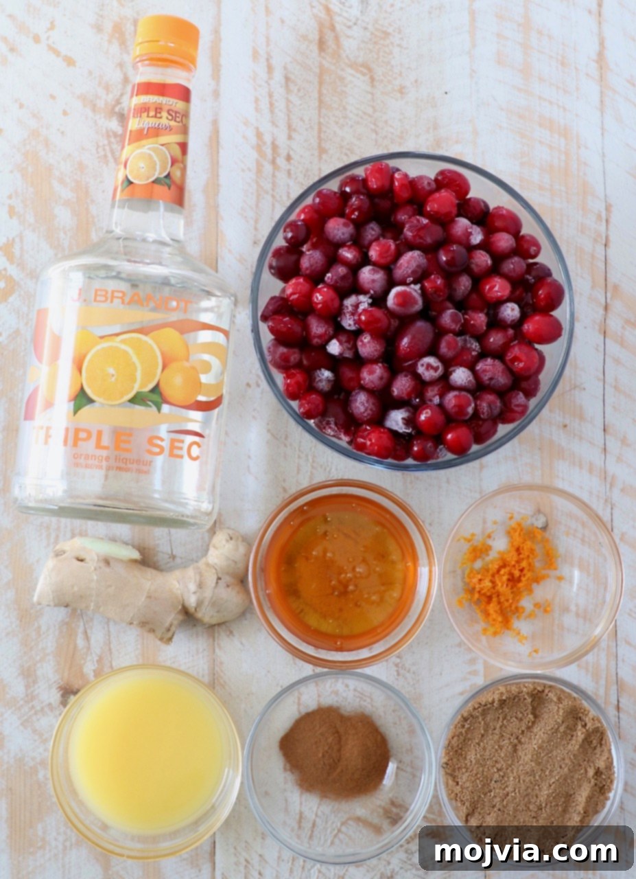 Fresh ingredients for cranberry glaze, including cranberries, orange, ginger, and honey.