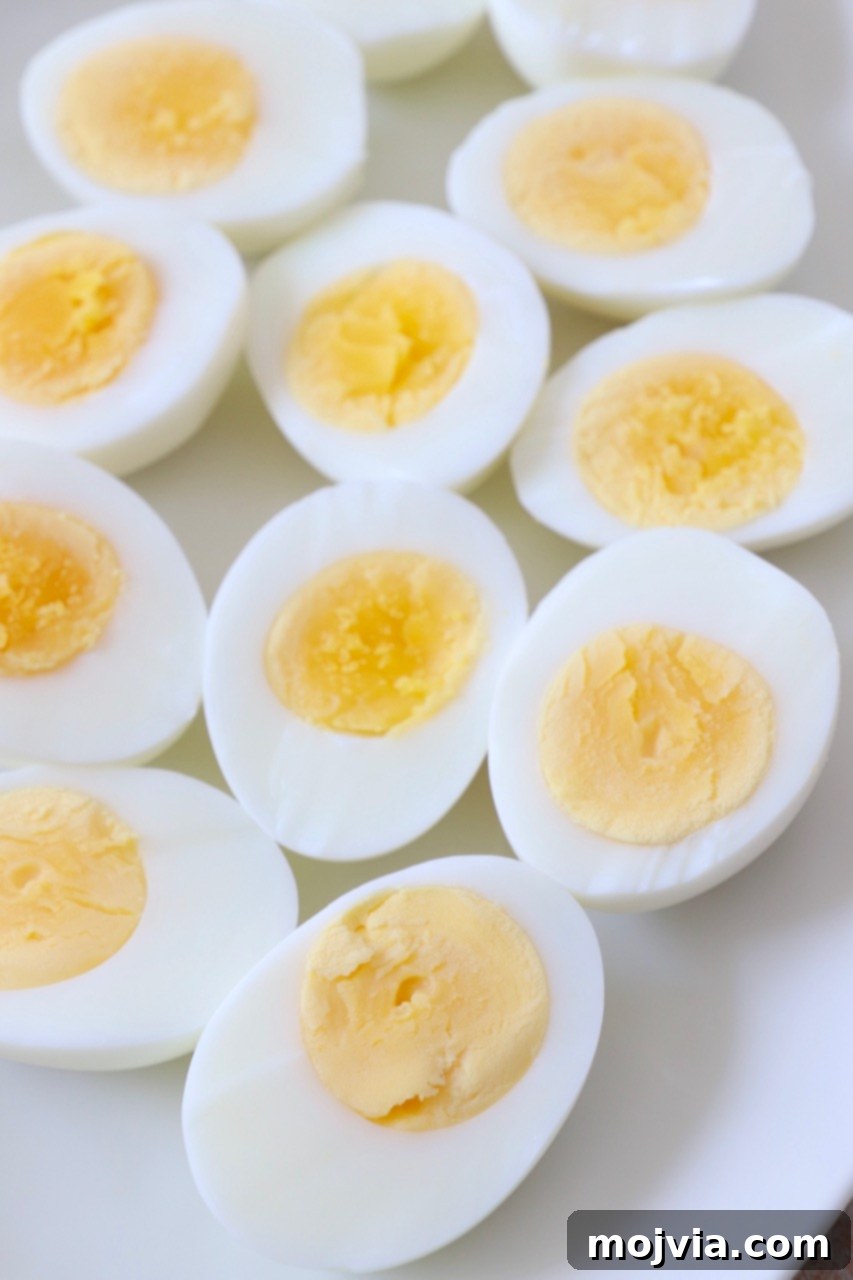 Perfectly sliced hard-boiled eggs on a white plate, showcasing creamy yolks