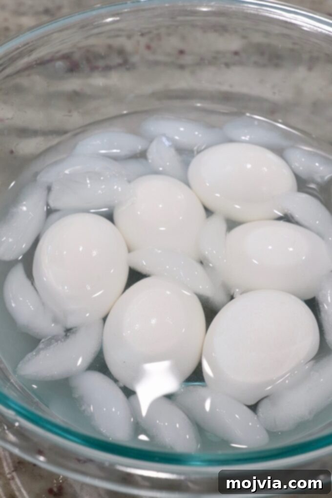 Hard-boiled eggs resting in a glass bowl filled with ice water for cooling