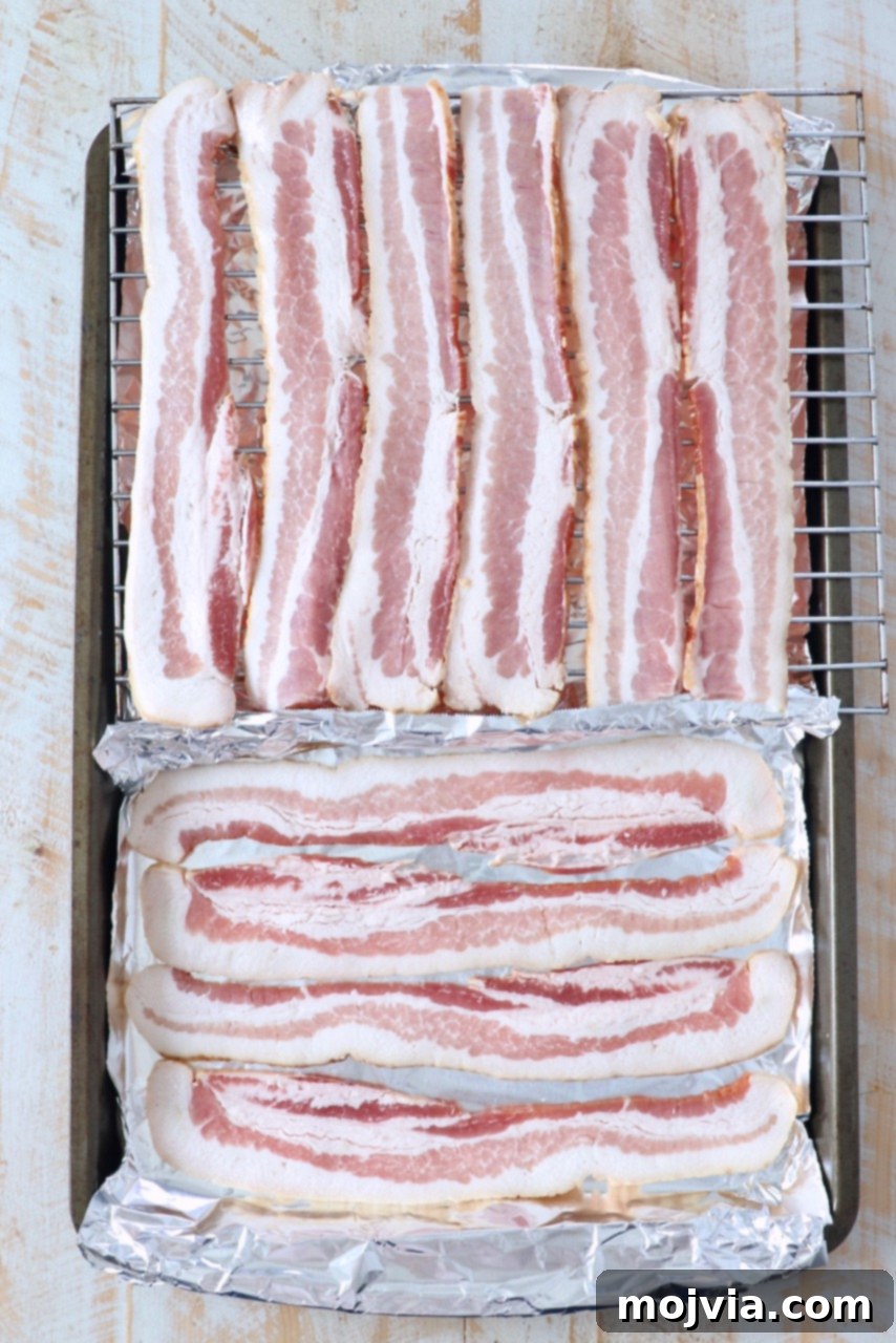 uncooked bacon strips arranged on a baking sheet lined with foil