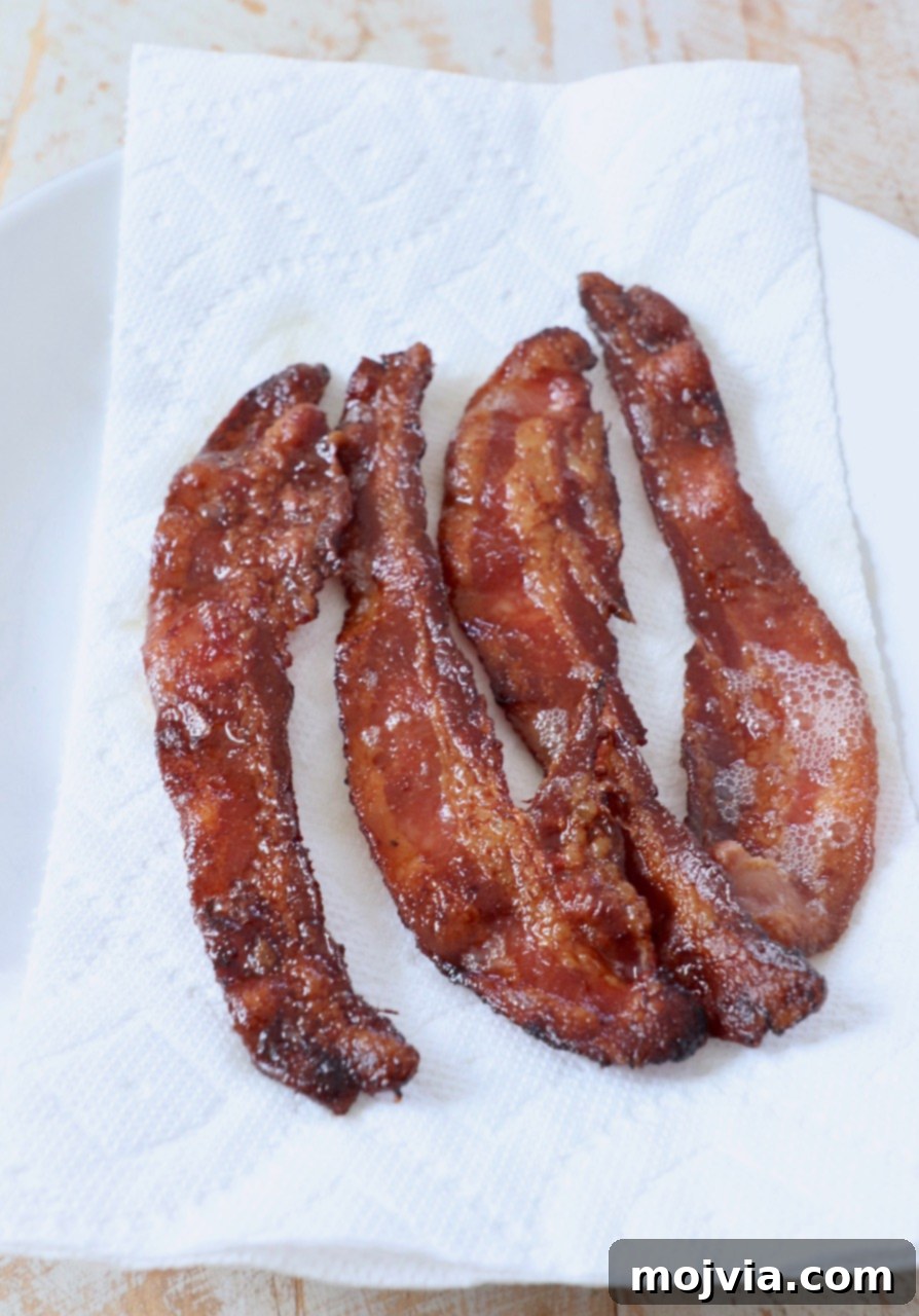cooked crispy bacon draining on a paper towel lined plate