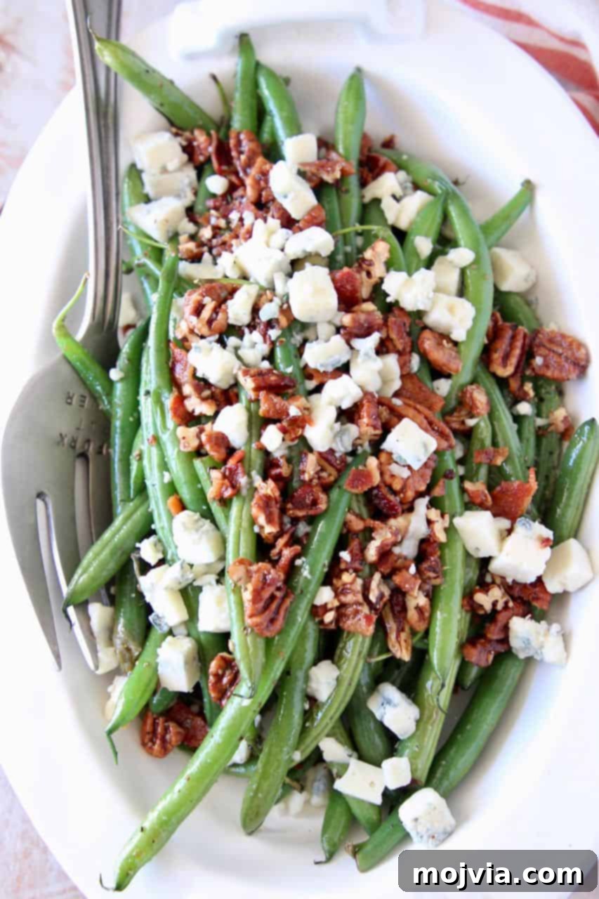 Fresh green beans in bowl topped with bacon crumbles, chopped pecans and blue cheese