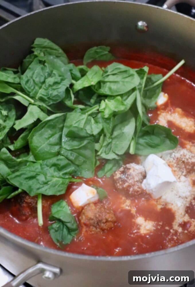 Ultimate Comfort Meatball Soup 7 spinach and cheese in pot of soup