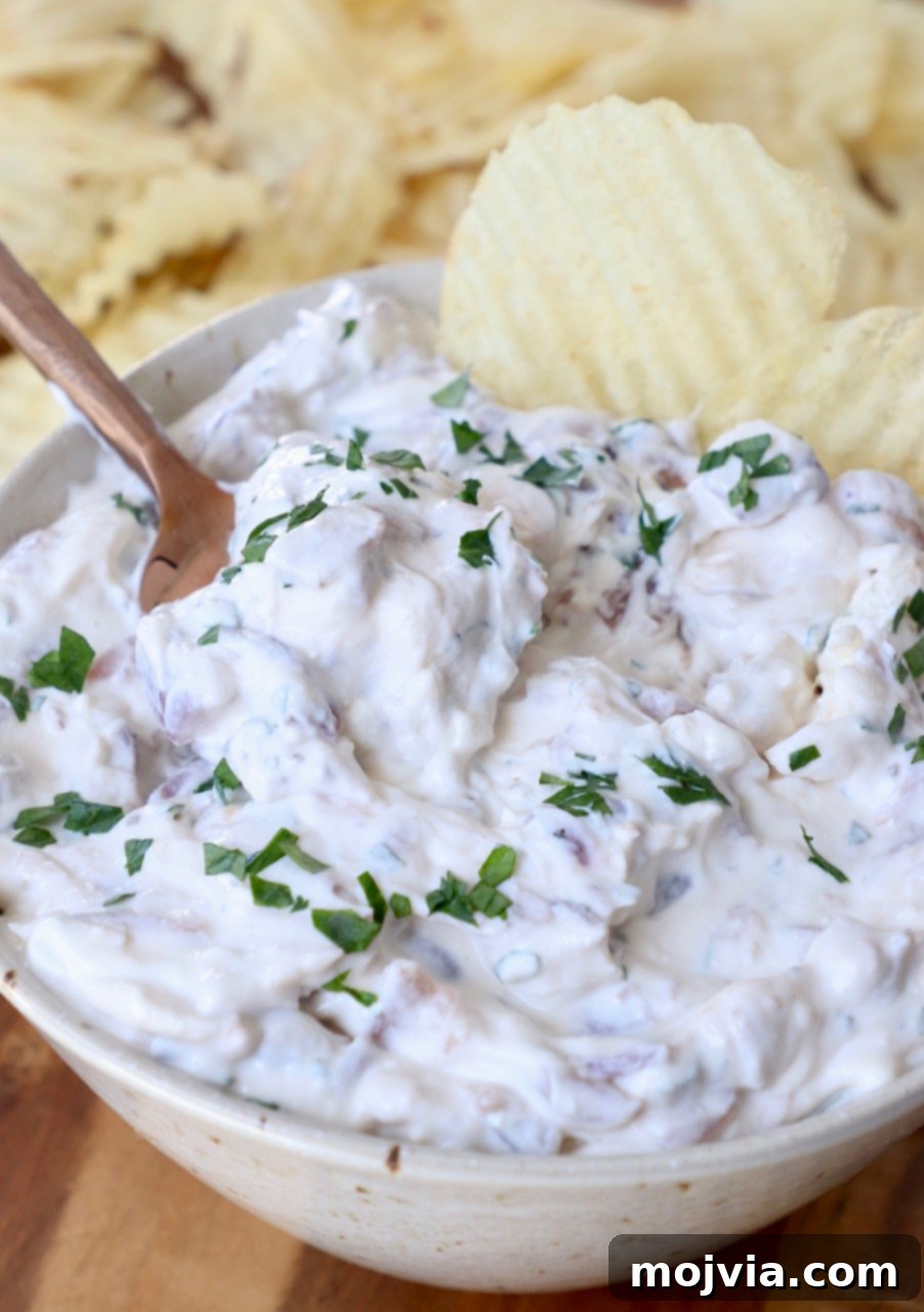 Crafting Irresistible Caramelized Onions 15 A bowl of creamy French Onion Dip, generously topped with caramelized onions, served with wavy potato chips.