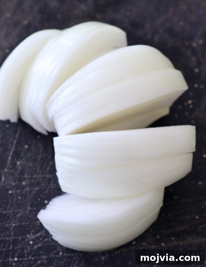 Crafting Irresistible Caramelized Onions 6 Evenly sliced pieces of onion laid out on a cutting board, showcasing the correct thickness for caramelization.