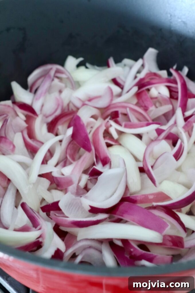 Crafting Irresistible Caramelized Onions 9 Freshly sliced onions added to a hot skillet with melted butter, evenly spread out.