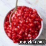 pomegranate arils in bowl with spoon