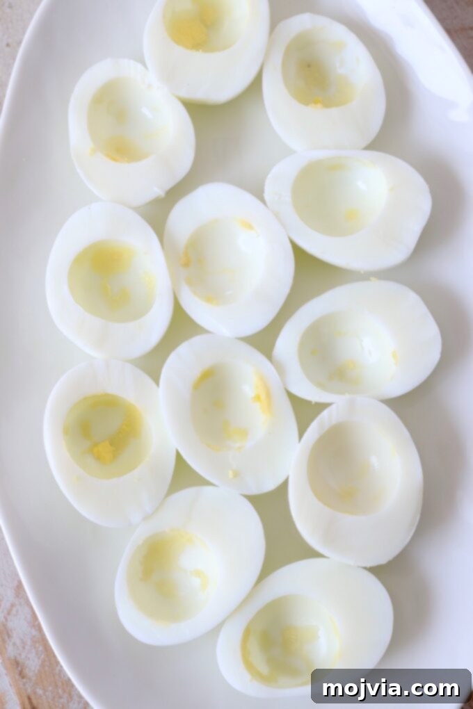 Family Favorite Deviled Eggs 4 hard boiled egg whites on plate with the yolks removed