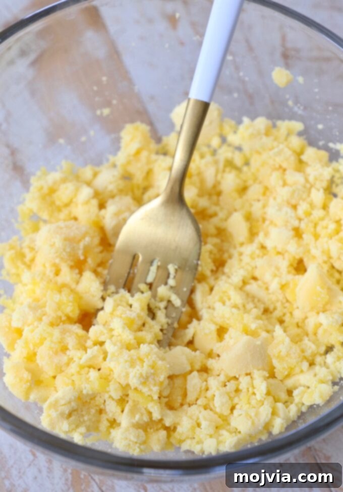 Family Favorite Deviled Eggs 6 smashed egg yolks in glass bowl with fork
