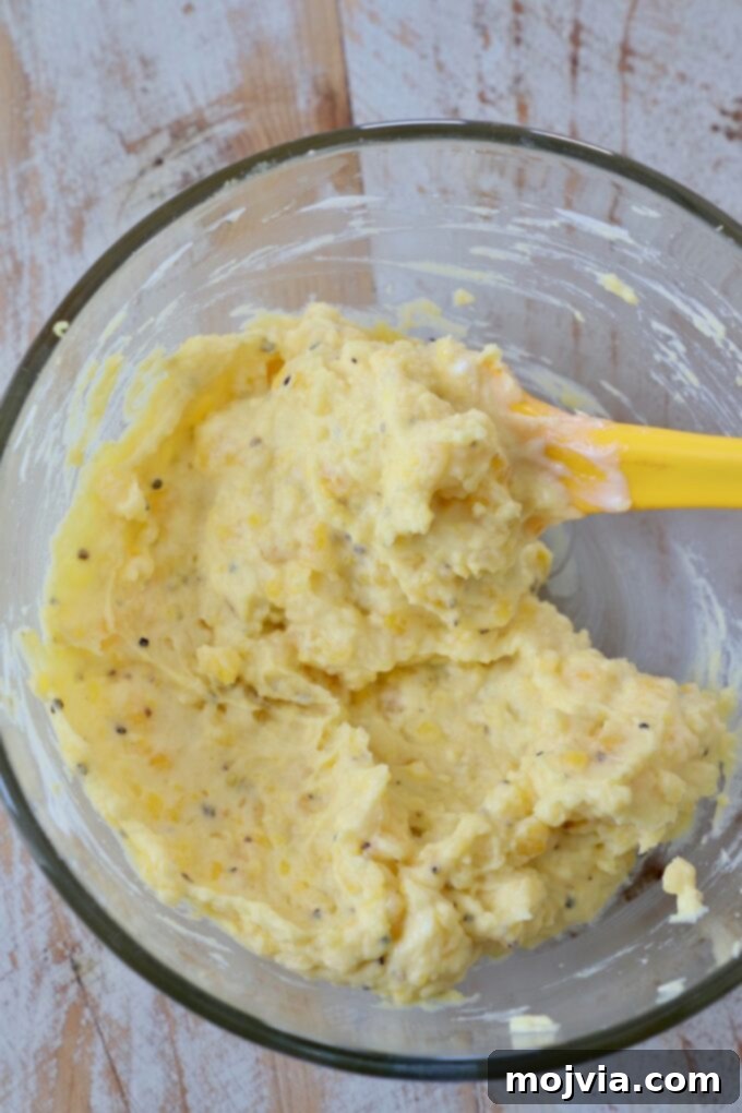Family Favorite Deviled Eggs 7 filling for deviled eggs in glass bowl with yellow spatula