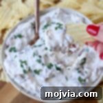 hand dipping chip into onion dip in bowl