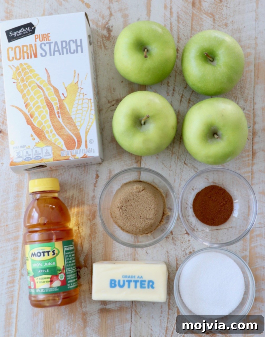 Fresh ingredients laid out for making homemade apple pie filling, including apples, butter, sugars, and spices.