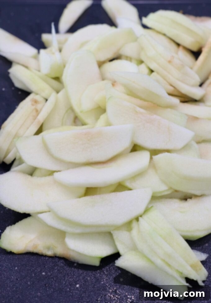 Thinly sliced apples neatly arranged on a cutting board, ready for cooking.