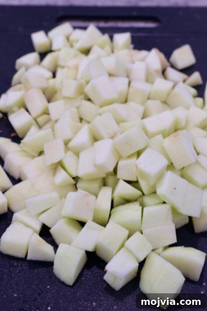 Fresh apples diced into small, even cubes on a cutting board, prepared for the filling.